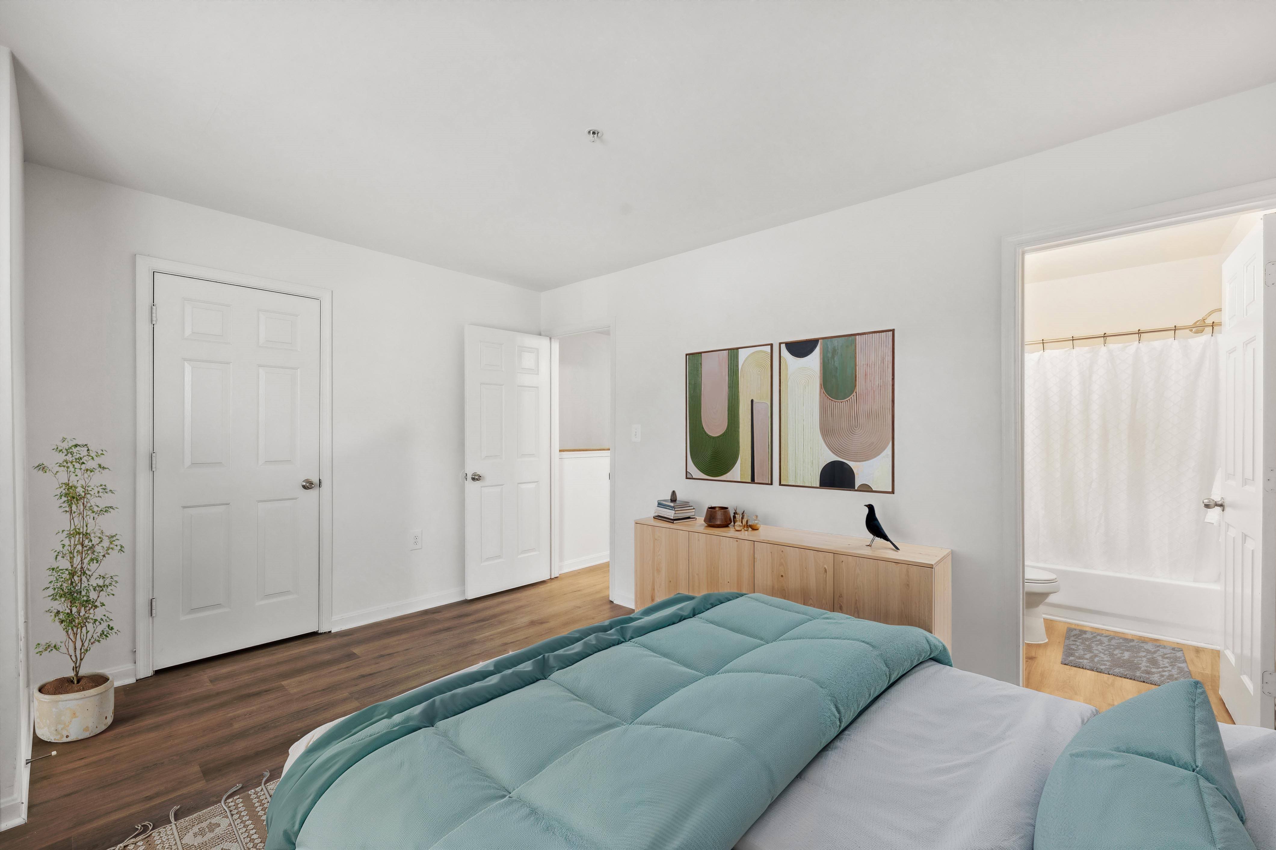 A bedroom with a bed in the center and a painting on the wall.